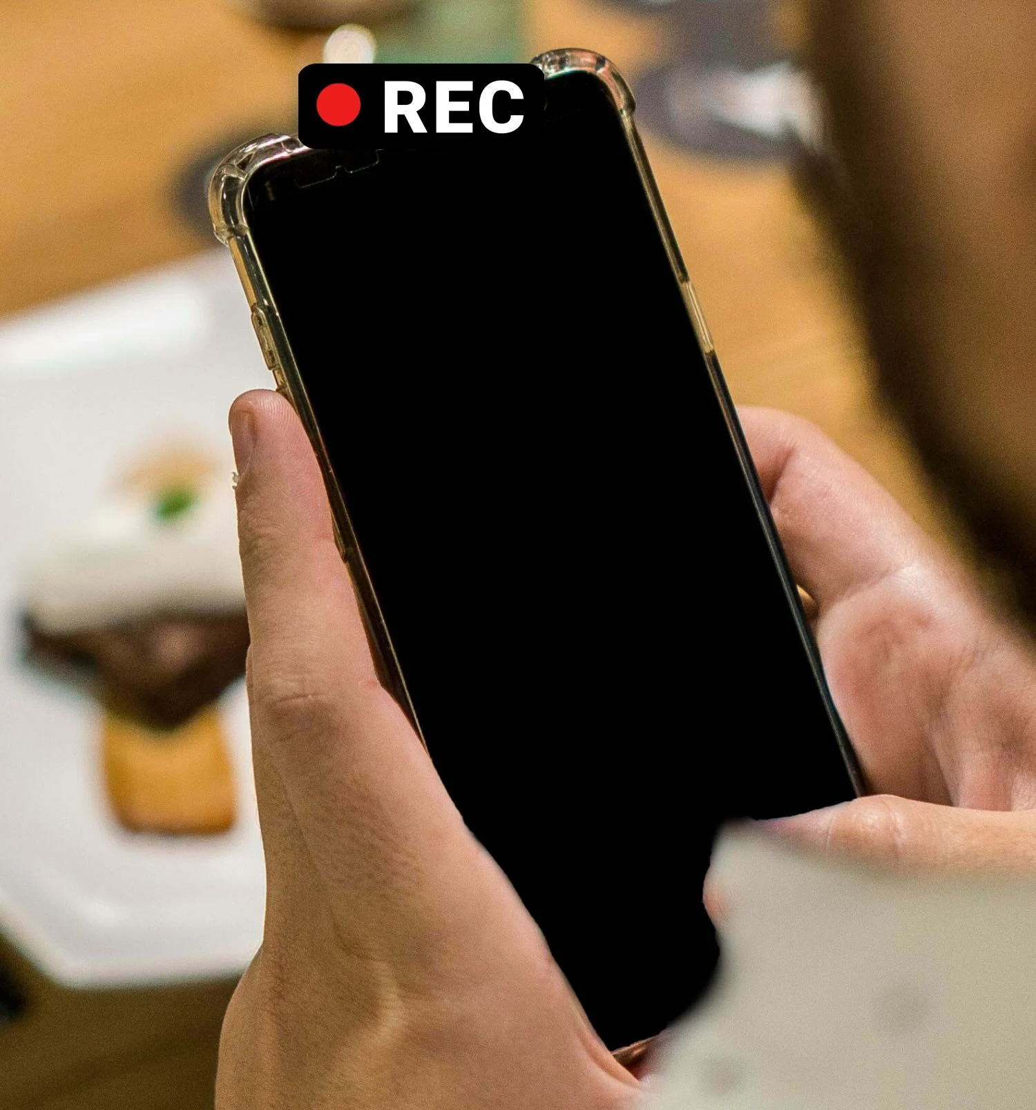 Phone with a black screen recording a video in a café with the Dark Cam app